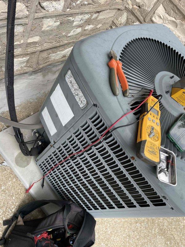 Replaced failed dual capacitor on outdoor condensing unit. Removed defective 40/5 MFD capacitor, installed new TITAN PRO replacement, and verified proper electrical connections. Tested unit operation with multimeter to confirm proper voltage readings and successful system startup.