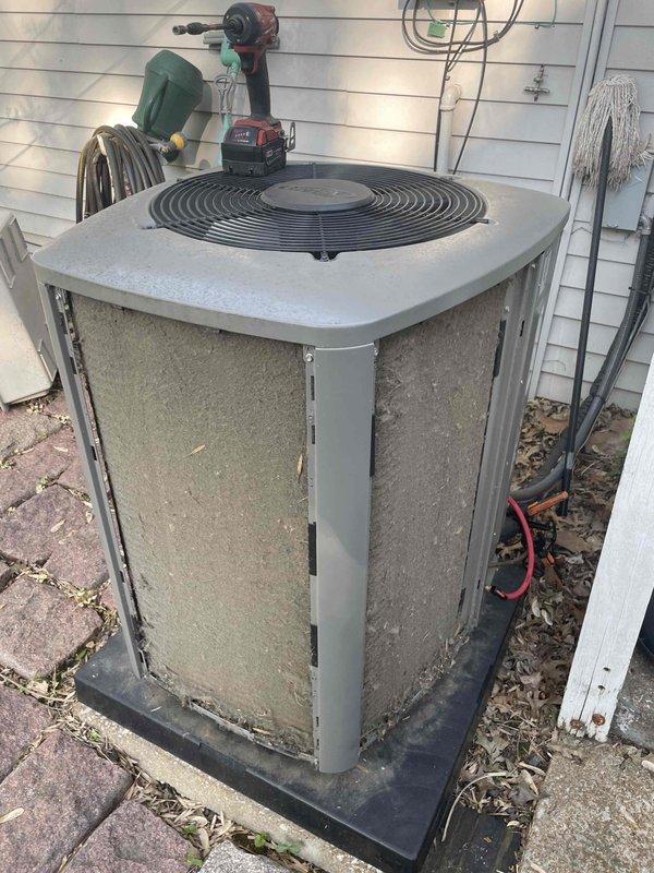 Completed comprehensive cooling system tune-up on a 2-year-old residential AC unit located in backyard. Performed standard maintenance protocol including inspection of condenser unit, cleaning of exterior panels which showed significant dirt accumulation, and verification of system operation. Documented unit condition with photos showing ductwork components and outdoor condenser unit with service gauges connected for refrigerant pressure testing and system diagnostics.