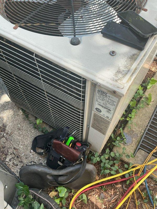Responded to no-cooling complaint on 40-year-old residential air conditioning system. Upon arrival, performed diagnostic evaluation of outdoor condenser unit and indoor air handler located in attic space. Inspected electrical connections, refrigerant lines, and condensate drainage system to identify cause of reported water leak and unit failure. Documented equipment condition with photographs showing weathered condenser unit with visible vegetation growth and aging components, as well as attic-mounted air handler with PVC drain lines. System assessed for operational status and potential repair recommendations given advanced age of equipment.