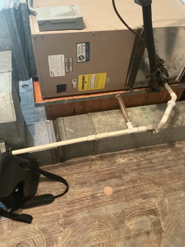 Responded to no-cooling complaint on 40-year-old residential air conditioning system. Upon arrival, performed diagnostic evaluation of outdoor condenser unit and indoor air handler located in attic space. Inspected electrical connections, refrigerant lines, and condensate drainage system to identify cause of reported water leak and unit failure. Documented equipment condition with photographs showing weathered condenser unit with visible vegetation growth and aging components, as well as attic-mounted air handler with PVC drain lines. System assessed for operational status and potential repair recommendations given advanced age of equipment.