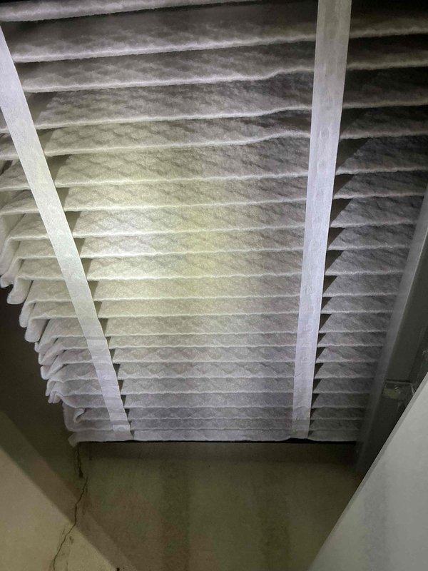 Completed preventive maintenance tune-up on two air conditioning units located on side of residential property. Inspected blower motor assembly, which showed dust accumulation on housing and electrical connections; documented condition with photographs for service records. Evaluated air filtration system and found return air filter heavily soiled with significant dust and debris buildup throughout pleated media, indicating restricted airflow; filter replacement recommended to restore proper system efficiency and indoor air quality.