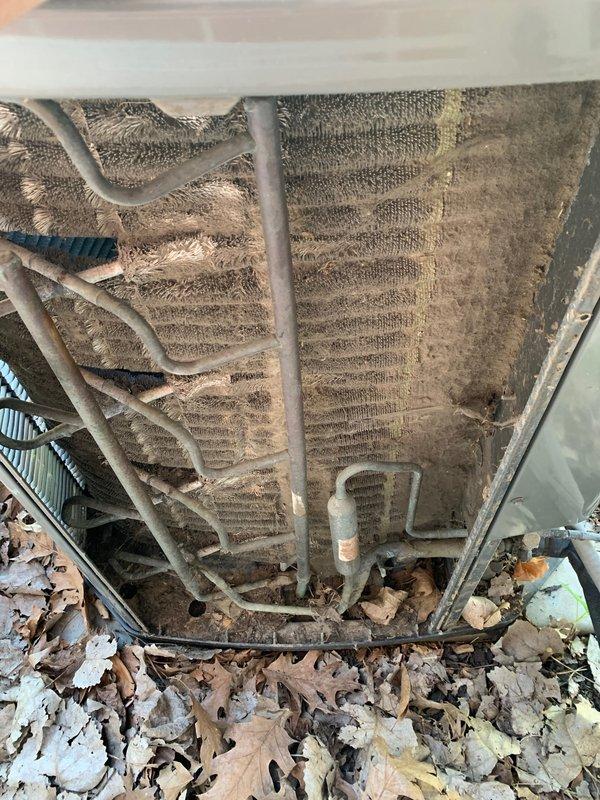 Completed comprehensive cooling system tune-up on 23-year-old residential air conditioning unit located on side of home. System inspection revealed significant dust and debris accumulation on evaporator coil fins and collection pan filled with organic matter including leaves and plant material. Performed standard maintenance procedures including cleaning of coil assembly, removal of debris from drain pan, inspection of refrigerant lines and electrical connections, and verification of proper system operation.