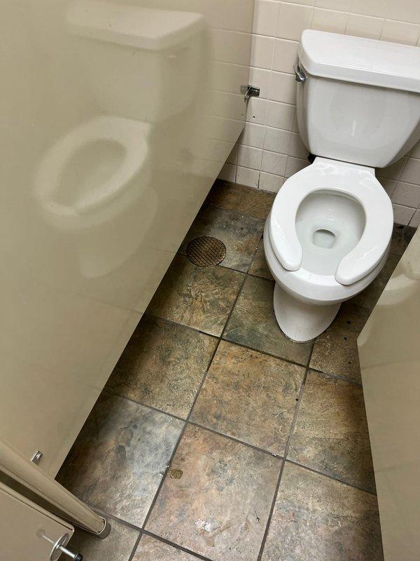 Responded to clogged drain issue in men's restroom facility. Upon arrival, assessed both toilet and urinal fixtures for drainage problems. Utilized plunger to clear obstruction in floor drain system. Verified proper water flow and drainage function in all fixtures before completing service. Restroom returned to full operational status.