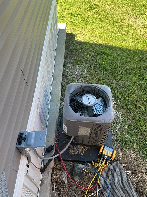 Responded to no-cool call on 4-year-old split system. Customer reported blower motor failure and frozen evaporator coil from previous night; unit had been turned off and allowed to thaw prior to arrival. Performed diagnostic testing on outdoor condensing unit using multimeter to check electrical components and compressor operation. Inspected indoor air handler and evaporator coil assembly located in laundry room closet. Verified blower motor functionality, checked refrigerant line connections, and tested system operation. Documented equipment condition with photos showing outdoor unit with test equipment connected and internal components of vertical air handler installation including evaporator coil and furnace assembly.