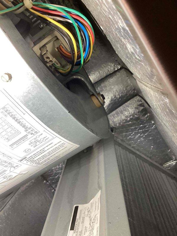 Responded to no cooling complaint on 10+ year old Carrier air handler unit located at ground level on side of home. Upon inspection, found blower motor issue preventing proper airflow through system. Accessed interior compartment and inspected electrical connections, wiring harness, and blower assembly. Verified all wire connections at junction box were secure and tested motor capacitor and relay components. Restored proper blower operation and confirmed adequate airflow throughout system. Unit cooling normally at time of departure.