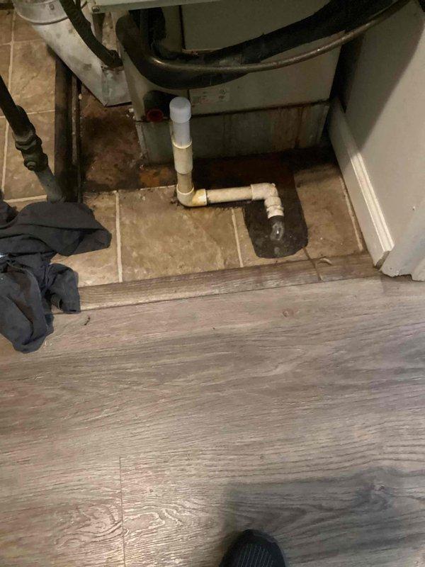 Responded to service call for water accumulation at base of furnace unit located in utility closet. Upon inspection, found drainage system experiencing backup issues with visible water staining on tile flooring beneath unit. Primary condensate drain line showed signs of improper drainage, causing water to pool around furnace base rather than evacuating through drain system. Inspected PVC drain assembly configuration and connections to identify source of drainage malfunction. Assessed condition of drain pan and surrounding plumbing connections. Documented water damage evidence on flooring and evaluated extent of moisture exposure around appliance base. Unit is over 10 years old and requires drainage system correction to prevent further water accumulation and potential equipment damage.