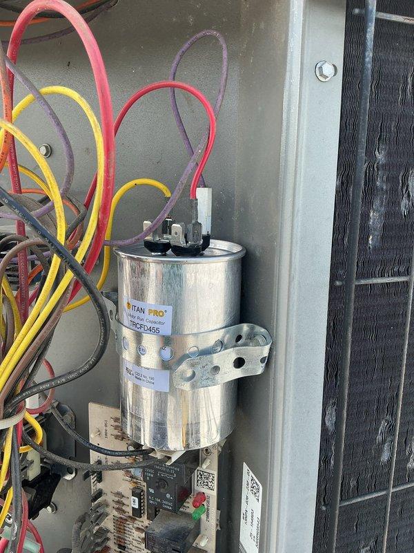 Replaced failed capacitor on HVAC unit with new TITAN PRO capacitor from truck stock. Removed old capacitor, installed replacement unit with proper mounting bracket, and reconnected all electrical terminals with appropriate color-coded wiring. System tested and operational upon completion.
