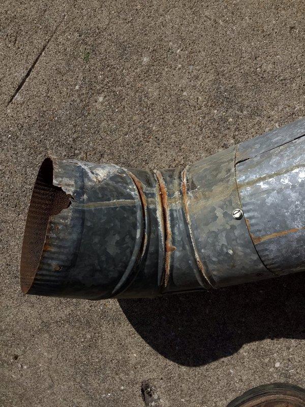 Responded to unit 10 basement for water heater exhaust connection. Inspected existing 5-inch galvanized vent pipe showing moderate rust staining and weathering at seams and joints. Connected exhaust ductwork to enable water heater installation, securing all connections with appropriate fasteners. Verified proper venting pathway through attic space with T-junction branch configuration. All metalwork secured and ready for water heater hookup.