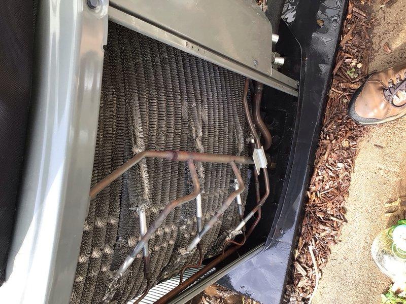 Completed preventive maintenance tune-up on a 4-year-old ground-mounted cooling unit. Removed top panel to access internal components, inspected evaporator coil assembly and refrigerant lines for proper condition, and noted accumulation of dirt and debris on coil fins requiring attention. Verified all accessible components, checked system operation, and ensured unit was secured upon completion of service.