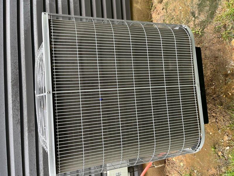 Completed comprehensive cooling system maintenance on single outdoor AC condenser unit. Performed standard tune-up procedures including inspection of protective grille, condenser coil, and external components. Unit found in operational condition with grille intact and coils accessible for service. Documented equipment condition through photographic records showing proper installation on grade-level pad adjacent to structure.
