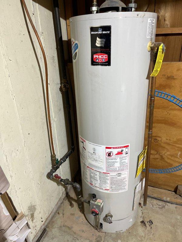 Installed a 50-gallon tall Bradford White gas water heater in the basement utility area. Connected copper supply lines with brass fittings and shutoff valves to the top of the unit, secured all plumbing connections, and verified proper venting configuration. Installation completed per manufacturer specifications in unfinished basement space with all required safety labels and documentation in place.