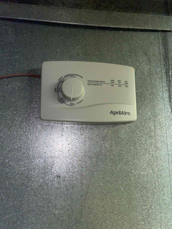 Installed AprilAire 600M whole-home humidifier unit to existing HVAC system. Connected unit to ductwork with galvanized metal transition elbow, mounted humidistat control on system cabinet, and established water supply line connection via brass valve fitting. System tested and confirmed operational with heating and cooling modes.