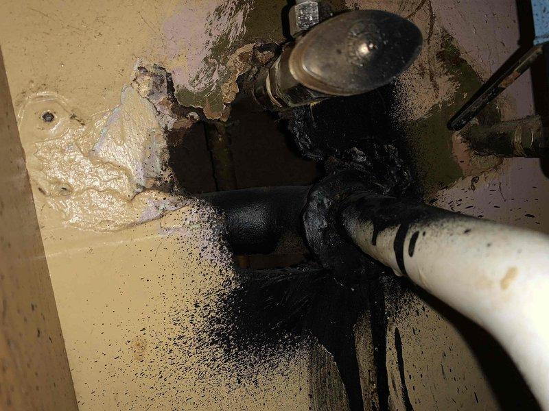 Responded to bathroom sink drainage issue and performed comprehensive assessment of plumbing system. Upon inspection, discovered clogged drain line was secondary to more significant underlying problems including active pipe leakage, severe corrosion on metal fittings and connections, and extensive water damage throughout the area. 

Documented deteriorated plumbing components with thick black viscous substance leaking from connection points, creating substantial staining on surrounding surfaces. White PVC piping showed age-related wear while metallic pipes displayed advanced corrosion, rust staining, and mineral deposit buildup. Multiple pipe connections exhibited signs of failure with ongoing leakage evident from fresh wet areas and drip patterns.

Found standing water accumulation on floor with biological growth including dark green and black mold/mildew covering multiple surfaces. Wall surfaces showed extensive deterioration with peeling paint, exposed substrate, and large sections 
