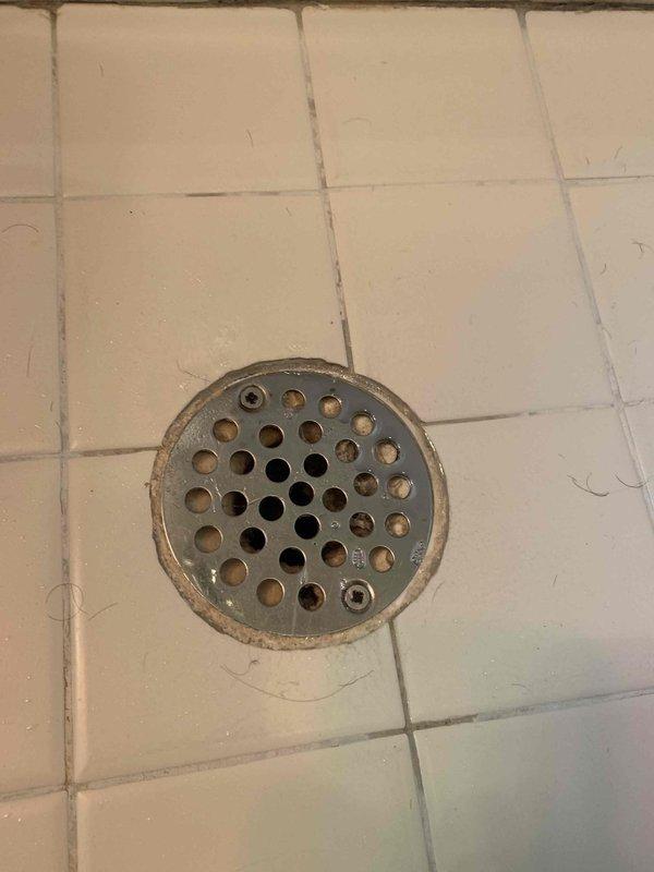 Responded to service call for dripping kitchen sink and slow-draining bathroom shower. Upon inspection, discovered significant vertical crack in kitchen sink basin extending from faucet base toward drain area, which was the source of the water leakage. Assessed bathroom shower drain and found metal drain cover with visible buildup and discoloration around perforations, restricting water flow. Documented both issues with photographs for repair recommendations. Customer advised that kitchen sink requires replacement due to structural damage and bathroom drain requires clearing and cleaning to restore proper drainage function.