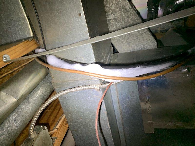 Responded to no heat call with reports of ice formation on refrigerant lines and cold air blowing from furnace. Upon inspection, discovered 9-year-old furnace system with excessive ice buildup on suction line, indicating refrigerant flow issues or potential heat pump reversing valve malfunction. Examined electrical connections at terminal block, which showed significant dust accumulation and aging components that could affect system operation. Assessed ductwork configuration and refrigerant line routing in attic space, noting proper insulation on copper lines but confirming abnormal ice formation consistent with heating mode failure. Documented existing conditions with photos showing HVAC components, electrical connections, and refrigerant line installation. Diagnosed system as requiring further evaluation of heat pump operation, reversing valve function, and potential defrost control issues causing unit to remain in cooling mode rather than heating mode.