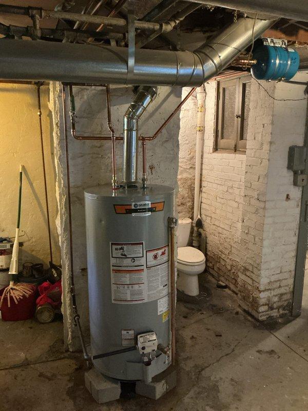 Installed 50-gallon gas short water heater in basement utility area, securing unit on cinder blocks for proper elevation and clearance. Connected copper supply lines, gas piping, and metallic vent system to existing infrastructure, ensuring proper venting through ceiling ductwork. Installed necessary pressure relief valve, shut-off valves, and verified all connections for proper operation and code compliance.
