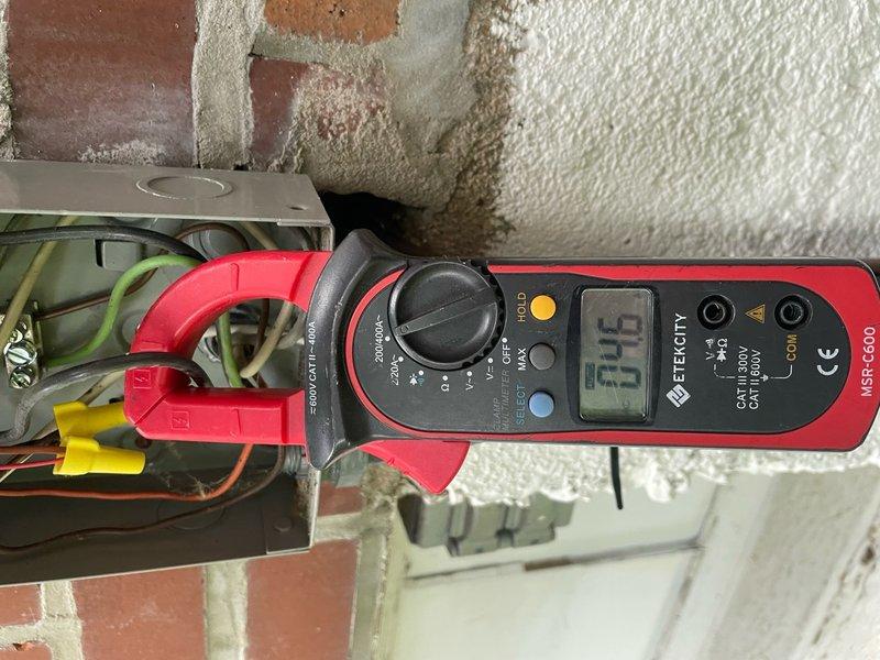 Responded to no cooling complaint on residential air conditioning unit located in backyard. Upon arrival, confirmed unit was running but delivering warm air to conditioned space. Performed electrical diagnostics using clamp meter to measure amperage draw at outdoor unit. Identified low amperage reading of 6.5 amps at compressor circuit, indicating potential compressor failure or refrigerant system issue. Documented electrical measurements at junction box and compressor terminals for diagnostic purposes.