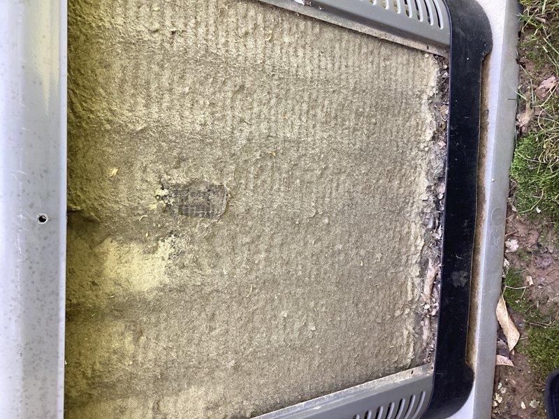 Responded to no cooling complaint on a 2-year-old air conditioning system. Upon inspection, discovered severely clogged air filter with extensive dust and debris accumulation, along with visible mold/algae growth indicating prolonged moisture exposure and lack of maintenance. Replaced contaminated filter to restore proper airflow and system operation, then performed system evaluation to verify cooling performance was restored.