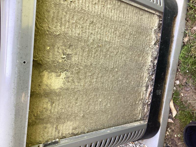 Responded to no cooling complaint on a 2-year-old air conditioning system. Upon inspection, discovered severely clogged air filter with extensive dust and debris accumulation, along with visible mold/algae growth indicating prolonged moisture exposure and lack of maintenance. Replaced contaminated filter to restore proper airflow and system operation, then performed system evaluation to verify cooling performance was restored.
