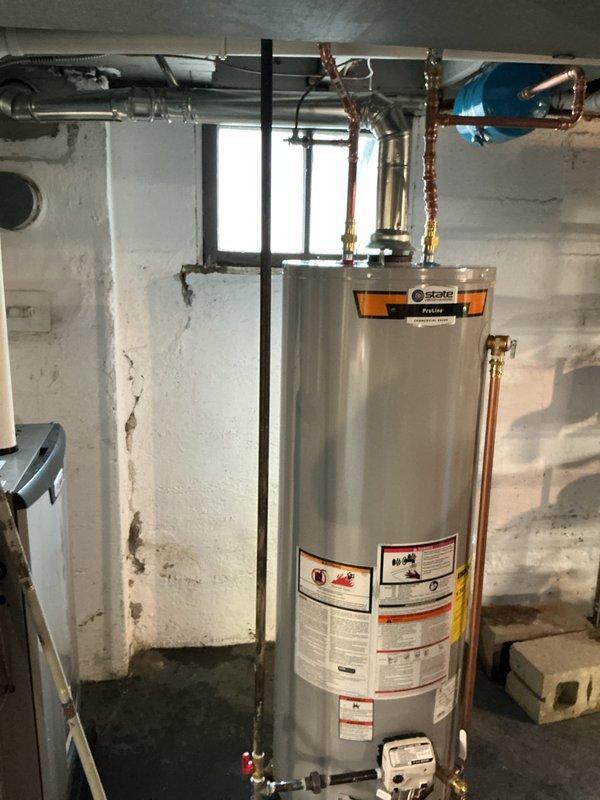 Installed a 40-gallon tall gas water heater in basement utility area with proper copper piping connections, expansion tank installation, and secure mounting. All connections were made to code specifications, with the blue expansion tank mounted horizontally and connected via copper piping to prevent thermal expansion issues. Installation completed in accordance with City of University City permit requirements, with all gas lines, water supply lines, and venting properly configured for safe operation.