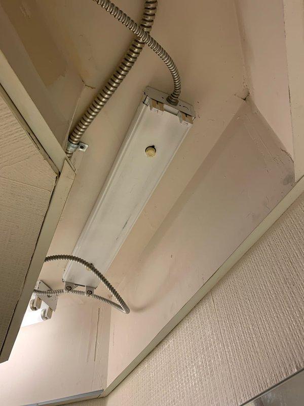 Replaced recessed fluorescent light fixtures in main bathroom area as requested. Customer supplied new fixtures for installation. Removed existing fixtures, installed flexible metallic conduit for electrical connections, and mounted replacement fluorescent lighting units to ceiling structure in accordance with electrical code requirements.