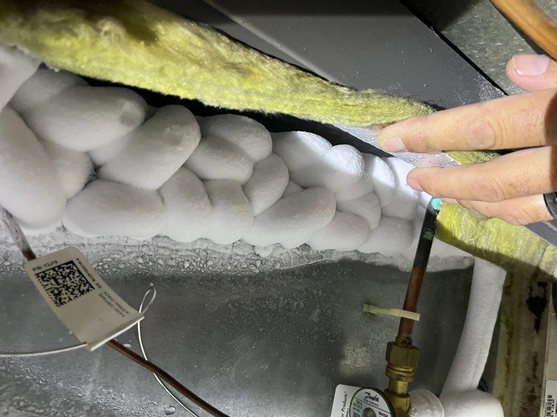 Responded to service call for non-operational Lennox system displaying error codes C2, A984, and E312. Upon inspection, discovered severe ice accumulation on the evaporator coil and refrigerant lines, indicating a complete system freeze-up. The ice buildup had formed thick, clustered formations along the suction line, preventing proper refrigerant flow and heat exchange. Identified compromised airflow as the primary cause, evidenced by displaced and deteriorated insulation around the air handler components. Assessed the 10-year-old system for underlying issues contributing to the freeze condition, including potential refrigerant charge problems, restricted airflow due to dirty filters or blocked return air, and possible thermostat or control board malfunctions triggering the error codes. Documented the frozen coil condition and insulation displacement with photographs for diagnostic reference. System required complete thawing before further diagnosis and repairs could be performed to r