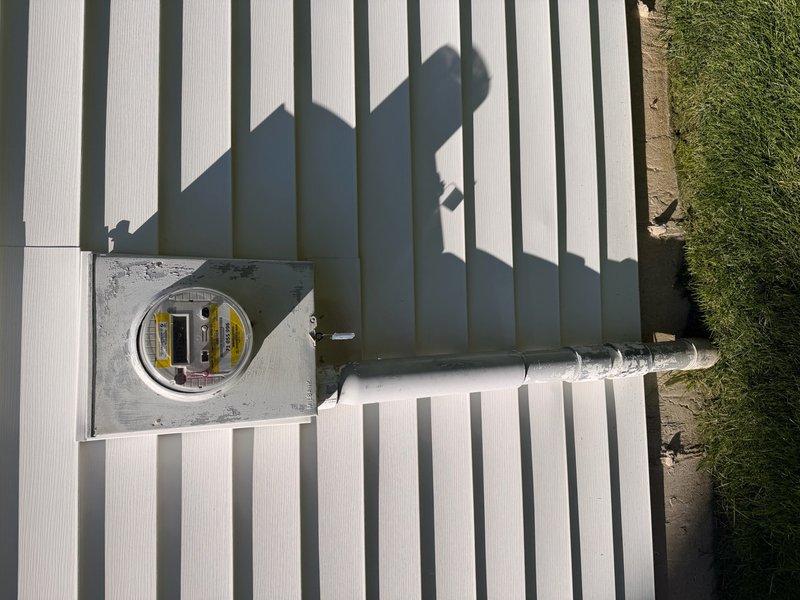Performed complimentary electrical inspection of exterior residential service equipment. Conducted visual assessment of main electrical meter enclosure, conduit routing, and mounting hardware on building exterior. Documented existing conditions through photographic records showing meter installation, protective enclosure with viewing window and safety labels, and metallic conduit run along exterior wall. Verified secure mounting of electrical components and noted current weathering patterns on outdoor-rated materials. All observations recorded for homeowner reference and future maintenance planning.