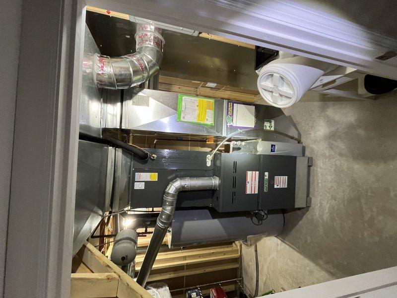 Responded to service call for water leakage near evaporator coils on 13-year-old residential air conditioning system. Upon arrival, inspected wall-mounted condensing unit and traced condensate drainage system through basement mechanical room. Located source of water leakage at evaporator coil drain pan and condensate line connections. Cleared blockage in condensate drain line, verified proper drainage flow, and confirmed drain pan integrity. Inspected air handler, ductwork connections, and associated PVC condensate piping for additional issues. System tested and cycled to ensure proper condensate removal with no further leakage detected.