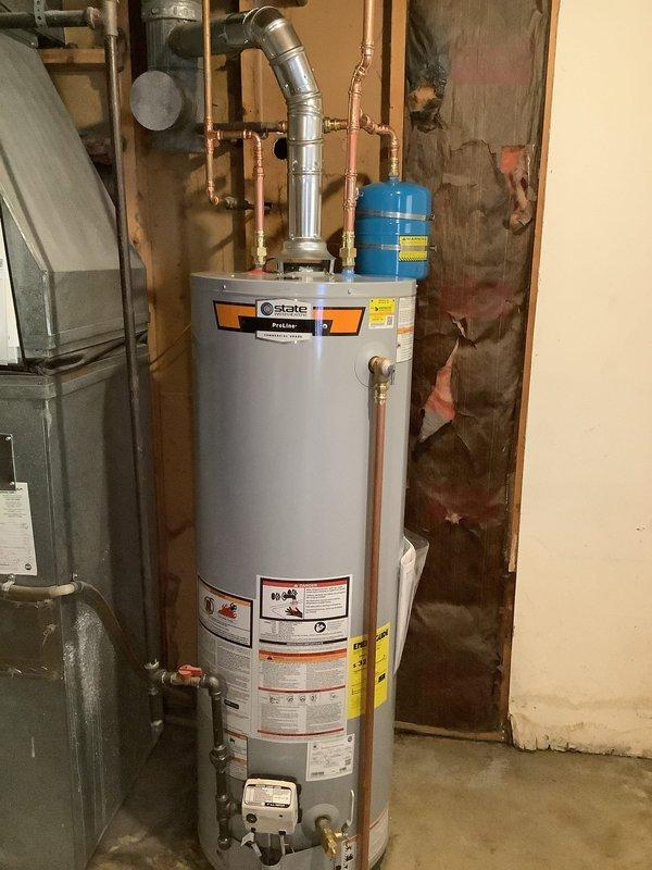 Installed a 40-gallon electric tall water heater in basement utility area, including complete copper piping connections with brass fittings, blue expansion tank mounted to supply lines, and proper venting configuration. Unit was set on white platform base with all code-compliant plumbing connections, pressure relief valve, and shut-off valves properly installed and tested for operation.