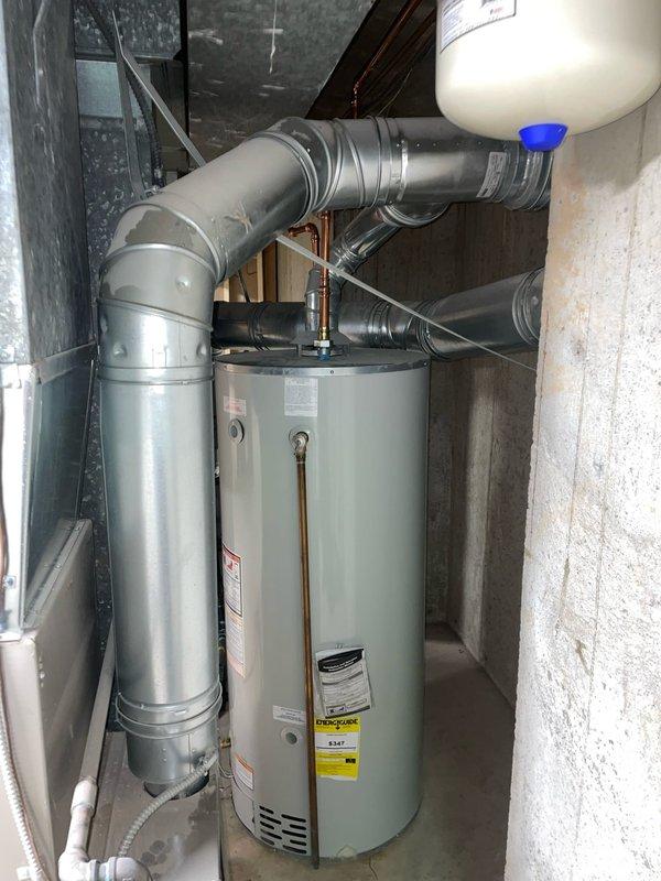 Responded to service call for flue gas spillage issue affecting water heater in basement mechanical room. Upon arrival, accessed property via lockbox and performed combustion safety inspection of heating equipment and venting system. Identified improper draft conditions causing combustion gases to spill from water heater flue rather than exhausting properly through vent system. Documented existing conditions with photos showing dual water heater installation, HVAC ductwork configuration, and Bradford White 75-gallon natural gas water heater (Model RG275H6N) with visible manufacturer specifications and safety labeling. Issue required further assessment and corrective action to ensure safe operation and proper venting of combustion appliances per code requirements.