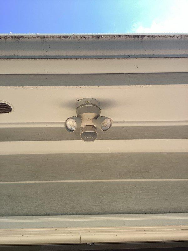 Installed exterior motion-activated security light fixture with dual adjustable heads on building soffit per customer request. Additionally installed two recessed LED light fixtures with trim rings in interior ceiling, completing all electrical connections and ensuring proper operation of motion sensor and lighting systems.