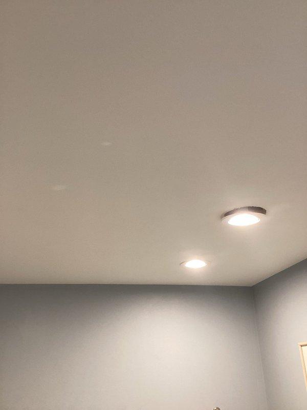 Installed exterior motion-activated security light fixture with dual adjustable heads on building soffit per customer request. Additionally installed two recessed LED light fixtures with trim rings in interior ceiling, completing all electrical connections and ensuring proper operation of motion sensor and lighting systems.