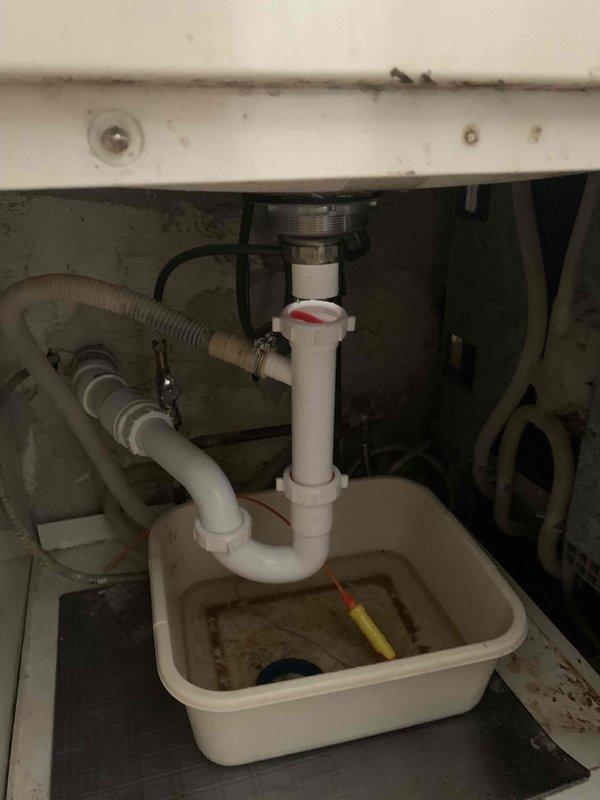 Responded to kitchen sink backup issue. Upon arrival, accessed cabinet beneath kitchen sink and inspected drainage system. Found P-trap assembly and connections associated with garbage disposal unit. Disassembled P-trap to clear blockage causing backup condition. Positioned collection basin to contain water and debris during service. Cleared obstruction from drain line, reassembled P-trap connections, and verified proper drainage flow restored to kitchen sink.