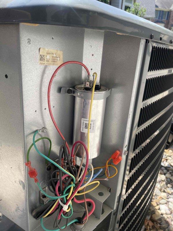 Returned to complete diagnosis following overnight thaw of frozen evaporator coil. Initial service call found no cooling condition with iced coil and inoperative blower motor. Inspected outdoor condenser unit and verified proper fin condition and cleanliness. Removed access panel to examine internal electrical components including capacitor and associated wiring connections. Documented system conditions with photos for service records.