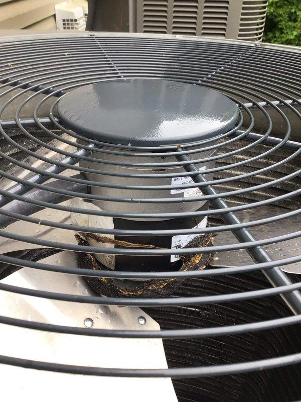 Responded to no cooling call on residential air conditioning unit less than one year old located in side yard. Customer reported system would not kick on. Upon arrival, performed diagnostic inspection of outdoor condenser unit. Found debris accumulation on fan blade and protective grille, which was preventing proper airflow and causing system shutdown. Cleared organic matter including leaves and debris from fan assembly and protective grille. Verified fan motor operation and confirmed proper startup sequence. System tested successfully with normal cooling operation restored.