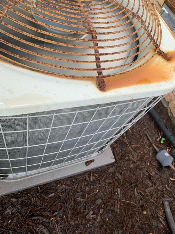 Completed preventive maintenance tune-up on residential HVAC system including outdoor condensing unit inspection and filter replacement. Installed new 16x25x1 air filter and performed exterior unit evaluation, noting significant rust accumulation on fan guard assembly while confirming operational status of white cabinet housing and protective grille components.
