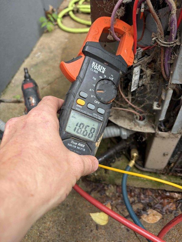 Responded to service call for 22-year-old Amana air conditioning system with reported noise coming from outdoor condensing unit during operation. Performed diagnostic testing on the condenser unit using clamp meter to measure electrical amperage draw, recording 186.8 amps during testing sequence. Connected manifold gauges with refrigerant hoses to system to evaluate operating pressures and assess compressor performance. Inspected condenser coils, fan motor operation, and electrical connections on outdoor unit to identify source of abnormal noise and determine necessary repairs for proper system function.