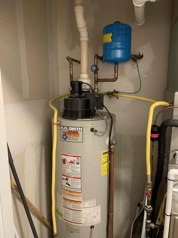 Replaced failed residential gas water heater with new 50-gallon A.O. Smith power vent unit due to existing heater failing to maintain pilot light and ignition issues. Installation included connecting copper supply lines, yellow flexible gas line, PVC power vent piping, pressure relief valve, and integration with existing blue pressure tank system. All connections tested and verified operational, with proper venting and safety labels affixed per code requirements.