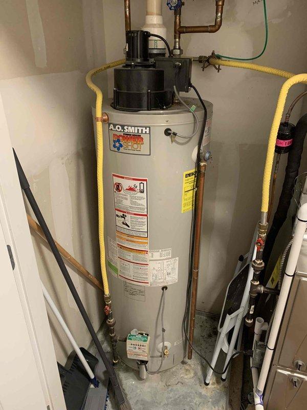 Replaced failed residential gas water heater with new 50-gallon A.O. Smith power vent unit due to existing heater failing to maintain pilot light and ignition issues. Installation included connecting copper supply lines, yellow flexible gas line, PVC power vent piping, pressure relief valve, and integration with existing blue pressure tank system. All connections tested and verified operational, with proper venting and safety labels affixed per code requirements.