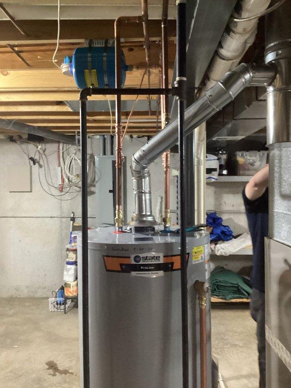 Completed installation of a 50-gallon gas tall water heater (State ProLine model) in residential basement. Connected all copper supply and discharge piping with appropriate brass fittings, installed gas line connections, and verified proper venting configuration. Unit was set up and prepared for delivery with all plumbing connections completed to code specifications.