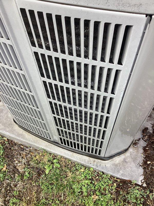 Completed preventive maintenance tune-up on a 2010 outdoor condensing unit located at ground level on side of home. Performed comprehensive system inspection, cleaned condenser coils which showed moderate accumulation of dirt, dust, and debris in louvers and grille areas, checked refrigerant levels, tested electrical connections, and verified proper operation of all components. Unit operational upon completion with no immediate repairs required.