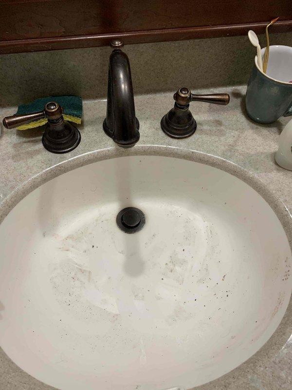 Responded to reported bathroom sink backing up and draining slowly. Upon arrival, inspected the undermount basin with bronze pop-up drain assembly and widespread three-piece faucet fixture. Accessed the P-trap assembly beneath the sink and found partial blockage causing slow drainage. Cleared obstruction from the P-trap and drain line, restoring proper water flow. Tested drainage multiple times to confirm issue was fully resolved. Inspected supply lines and shut-off valves while under cabinet—all connections found secure with no leaks detected.