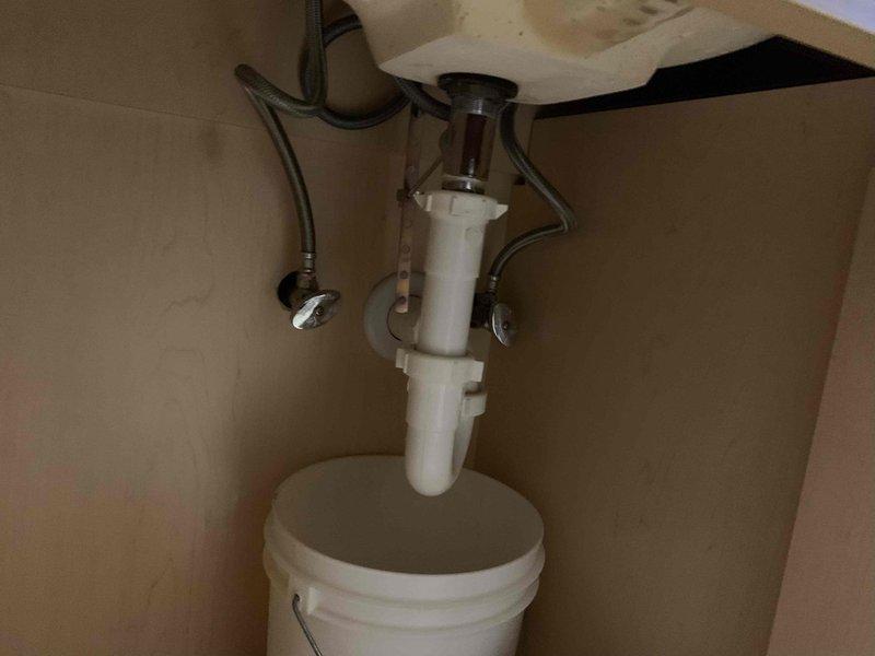 Responded to reported bathroom sink backing up and draining slowly. Upon arrival, inspected the undermount basin with bronze pop-up drain assembly and widespread three-piece faucet fixture. Accessed the P-trap assembly beneath the sink and found partial blockage causing slow drainage. Cleared obstruction from the P-trap and drain line, restoring proper water flow. Tested drainage multiple times to confirm issue was fully resolved. Inspected supply lines and shut-off valves while under cabinet—all connections found secure with no leaks detected.