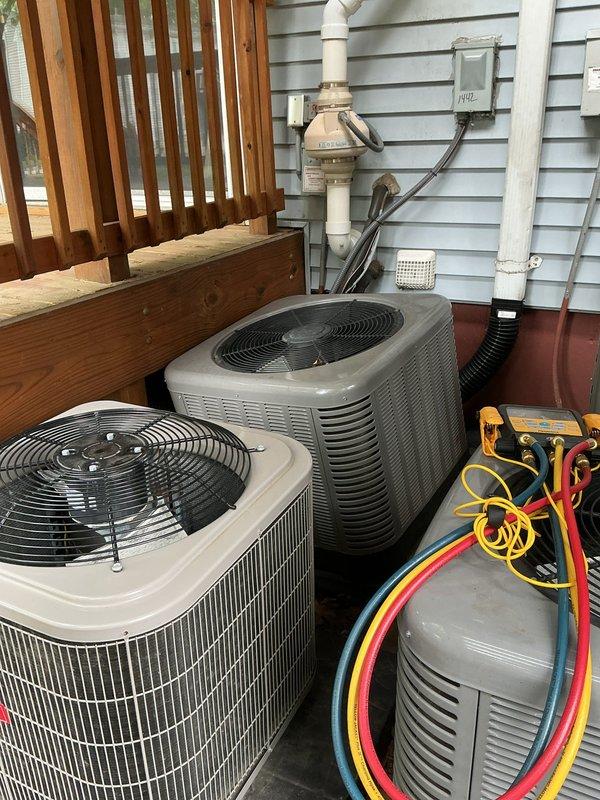 Responded to service call for tilting condenser unit at rear of property. Upon inspection, found Unit 10 condenser experiencing structural instability due to deteriorated pad support and settled deck foundation. Evaluated multiple outdoor condensing units positioned on wooden deck surface. Assessed compromised mounting surface and verified unit remained operational with no refrigerant leak detected. Documented existing conditions including weathered decking, proper electrical connections, and condensate drainage configuration. Recommended foundation reinforcement and pad replacement to prevent further tilting and potential refrigerant line damage.
