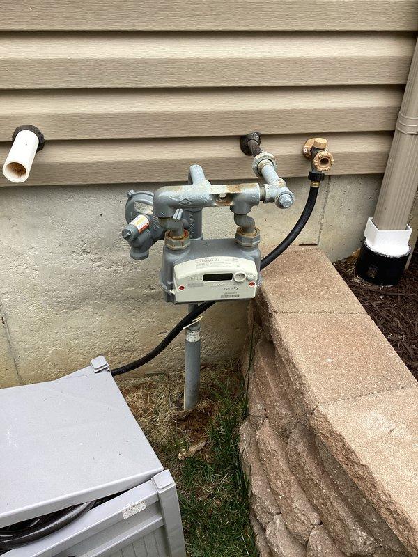 Completed electrical estimate for generator installation following HVAC technician turnover. Documented existing 200A main electrical panel with available breaker positions and assessed natural gas meter installation with supply piping configuration at exterior location. Photographed current utility infrastructure including gas meter assembly with shutoff valves, piping connections, and electrical service panel to determine equipment placement requirements and connection points for proposed generator system.