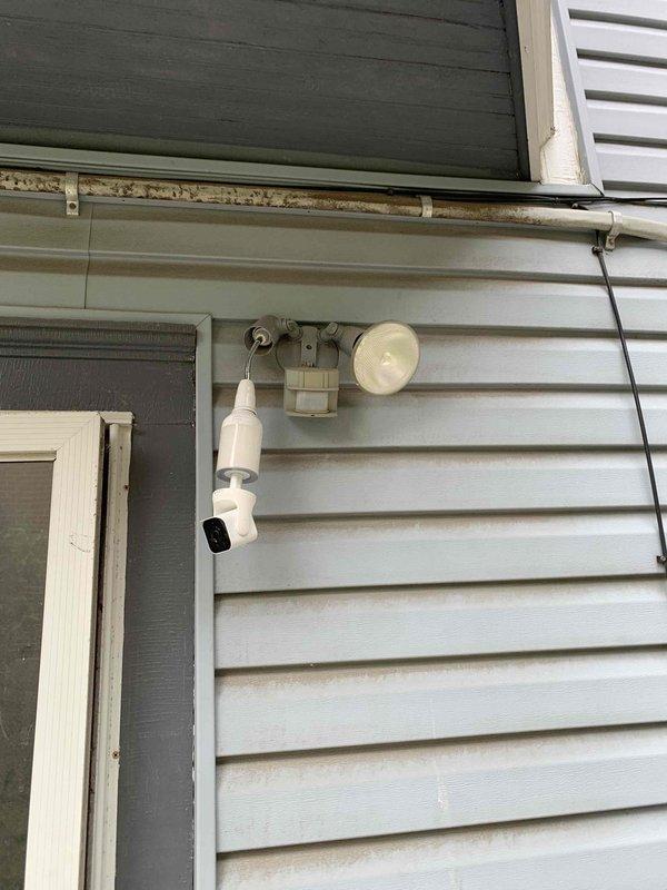 Installed new motion-activated security light fixture on exterior wall, replacing previous lighting setup. Successfully mounted dual-head LED motion sensor light to existing electrical junction box, ensuring proper weatherproofing and secure attachment to vinyl siding. Fixture is fully operational with motion detection capabilities for enhanced exterior security lighting.
