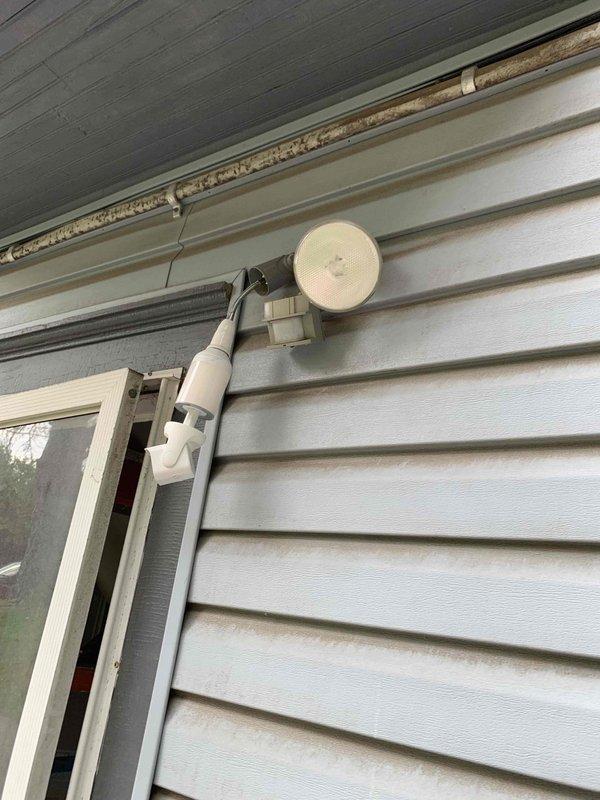 Installed new motion-activated security light fixture on exterior wall, replacing previous lighting setup. Successfully mounted dual-head LED motion sensor light to existing electrical junction box, ensuring proper weatherproofing and secure attachment to vinyl siding. Fixture is fully operational with motion detection capabilities for enhanced exterior security lighting.