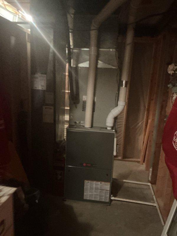 Responded to service call for non-operational A/C fan and reported moldy odor on four residential units over 10 years old located at rear of property. Performed system inspection revealing deteriorated insulation material at coil assembly junction and signs of moisture intrusion affecting heat exchanger components. Documented condition of basement-mounted furnace and HVAC equipment, noting dust accumulation on finned coils and refrigerant lines, which can restrict airflow and contribute to musty odors when combined with compromised insulation.