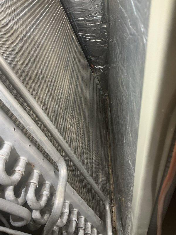 Responded to service call for non-operational A/C fan and reported moldy odor on four residential units over 10 years old located at rear of property. Performed system inspection revealing deteriorated insulation material at coil assembly junction and signs of moisture intrusion affecting heat exchanger components. Documented condition of basement-mounted furnace and HVAC equipment, noting dust accumulation on finned coils and refrigerant lines, which can restrict airflow and contribute to musty odors when combined with compromised insulation.