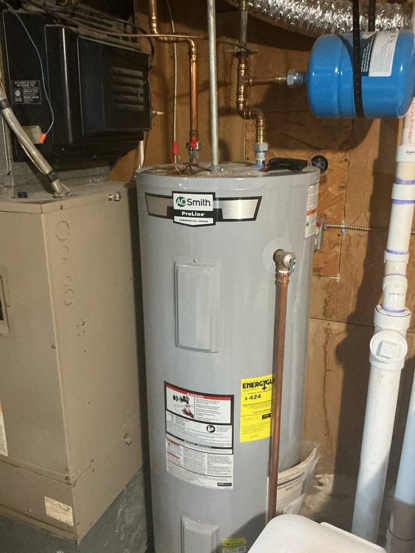 Responded to no hot water condition in basement. Completed warranty replacement of failed water heater with new AO Smith ProLine 50-gallon electric tall water heater model ENT 50 130. Removed old unit and retrieved warranty sticker for reimbursement processing. Installed new unit with proper connections to existing copper supply lines, pressure relief valve with discharge pipe, and electrical connections per manufacturer specifications. Verified all plumbing connections secure and system operational upon completion.